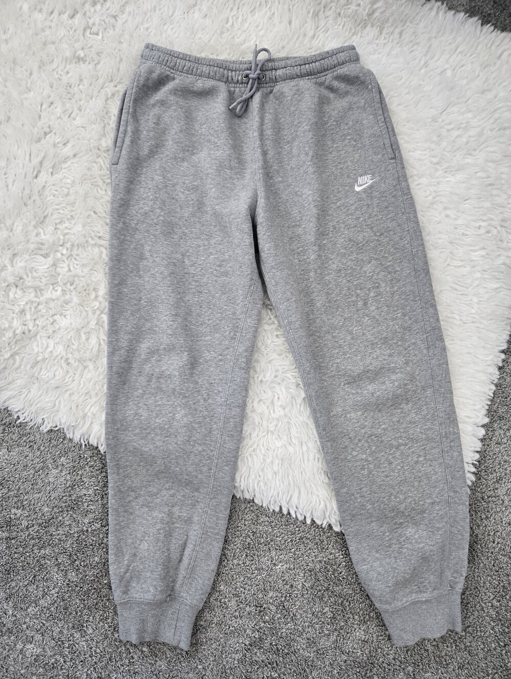 Nike Club Fleece joggers featuring an embroidered Swoosh logo. Grey. Size Medium